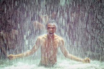 Man full of joy under waterfall